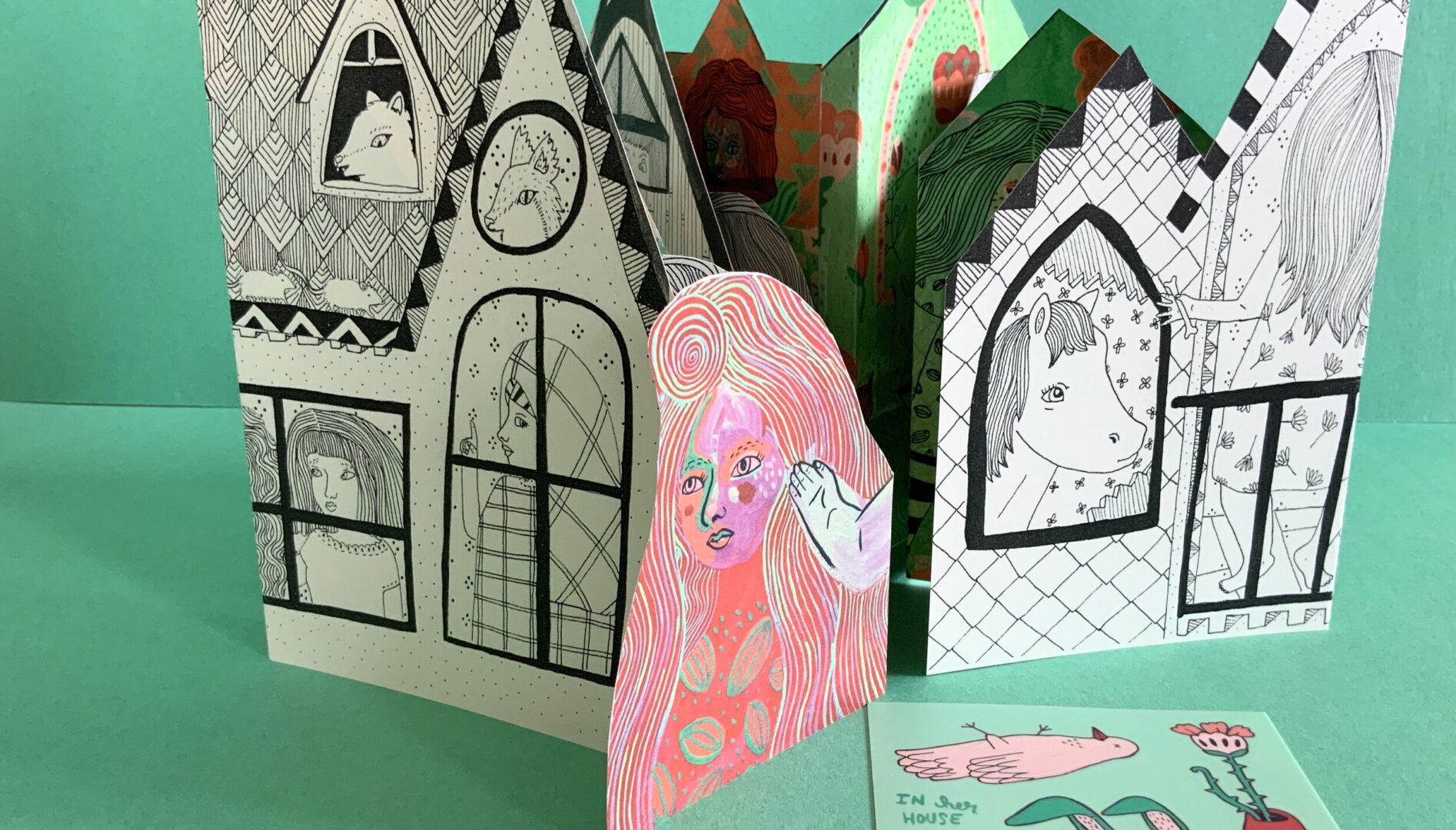 Photo of an illustrated house built of paper.