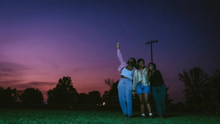 A group of people standing outside under a purple and pink evening sky.