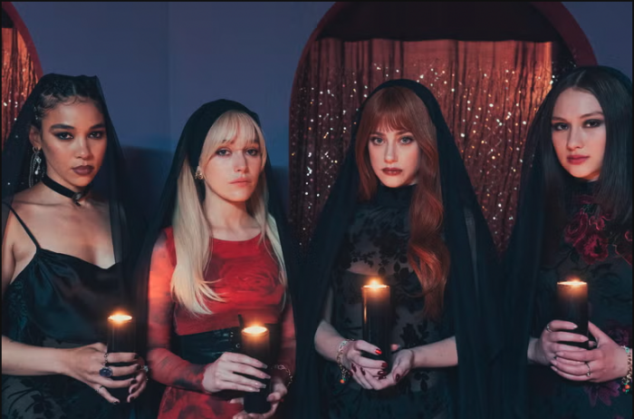 Four young women wearing veils and holding candles.