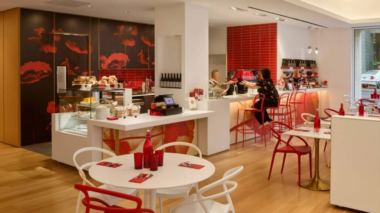 A café interior with a staff person behind the counter and a seated customer.