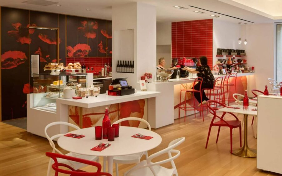 A café interior with a staff person behind the counter and a seated customer.