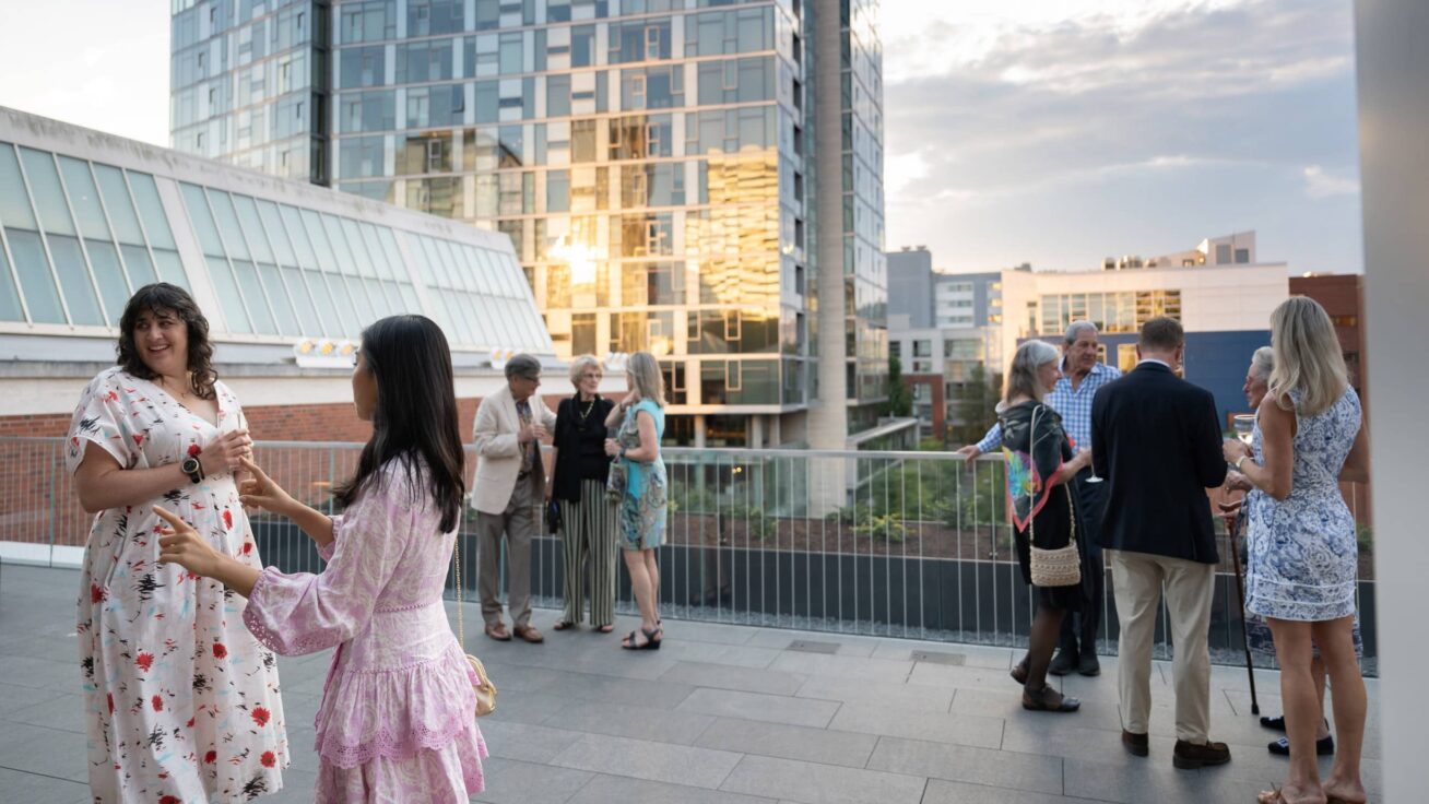 People standing and conversing on an open terrace.