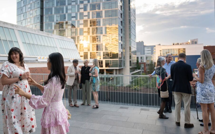 People standing and conversing on an open terrace.
