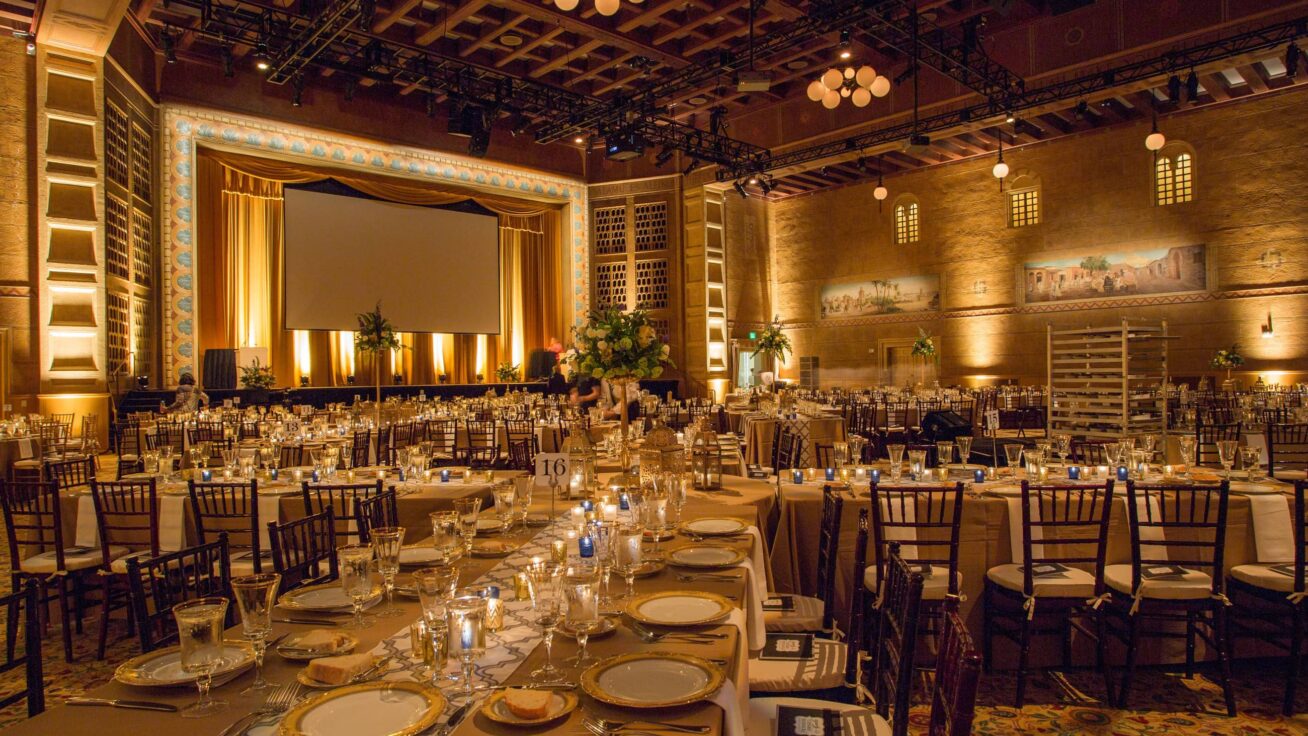 Large ballroom with many tables and place settings.