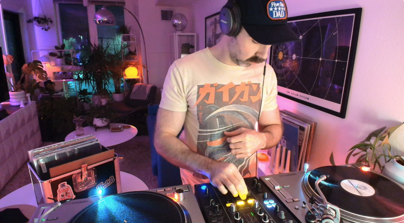 Video still of a DJ in his living room.