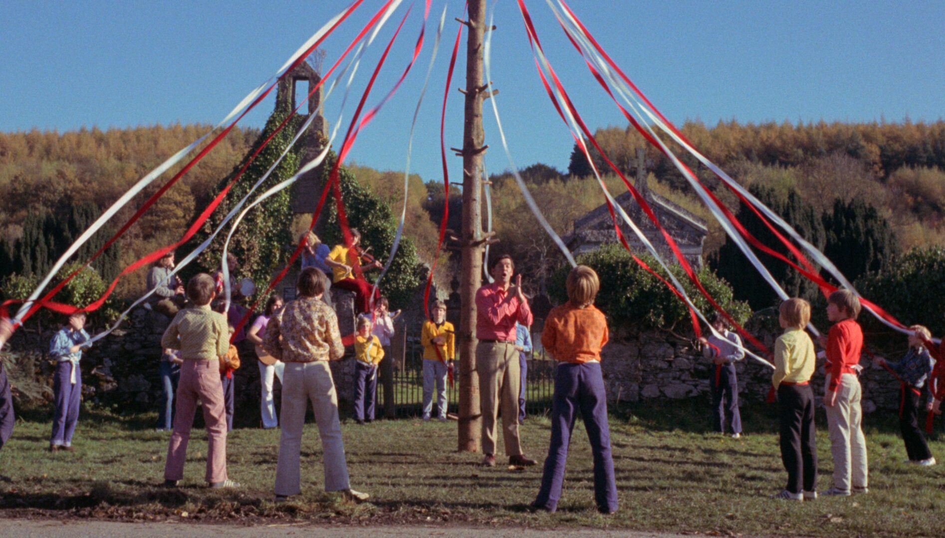 Film still of a group of people around a may pole.