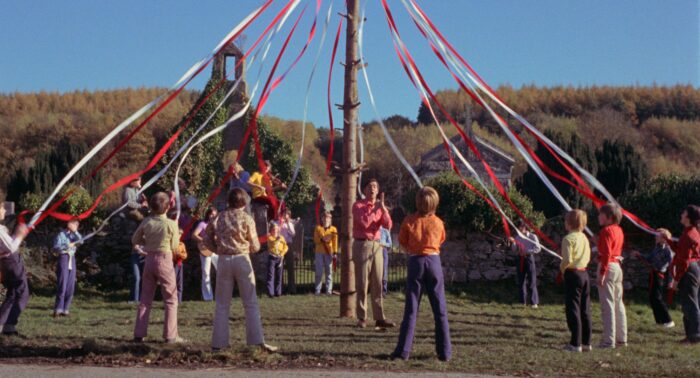 Film still of a group of people around a may pole.