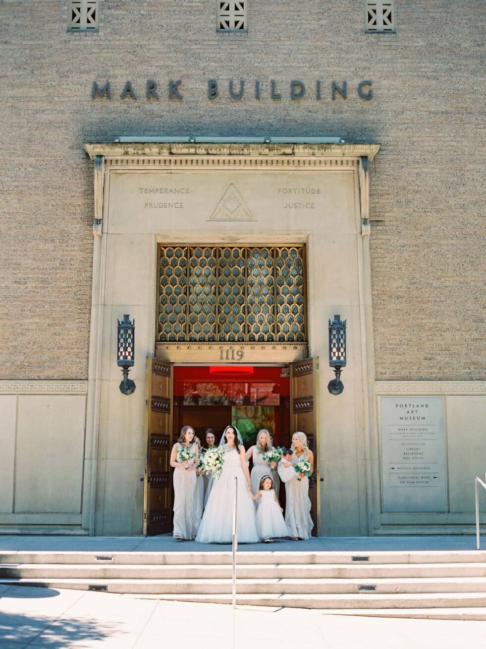 A wedding party standing in front of a building entrance.