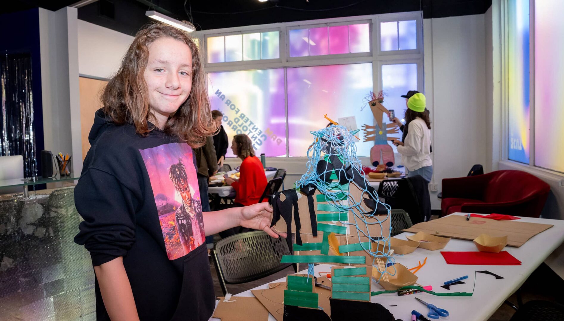 A young person standing next to a table.