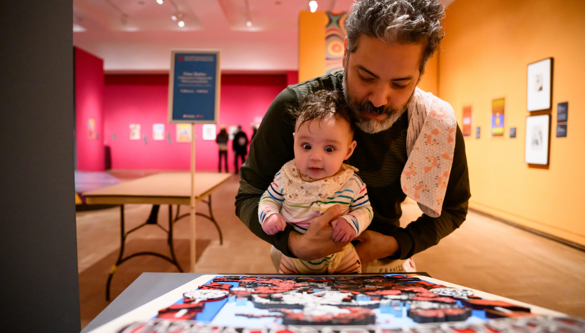 Photo of a man holding a baby in front of a Grateful Dead poster tactile art.