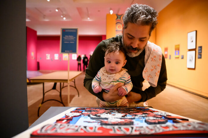 Photo of a man holding a baby in front of a Grateful Dead poster tactile art.
