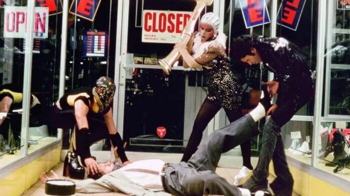 Three people in costumes beating up a man laying on the floor of a business.