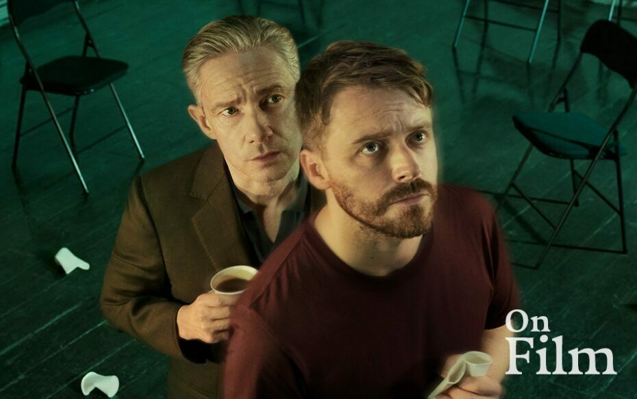 Film still of two men standing together and looking upward.