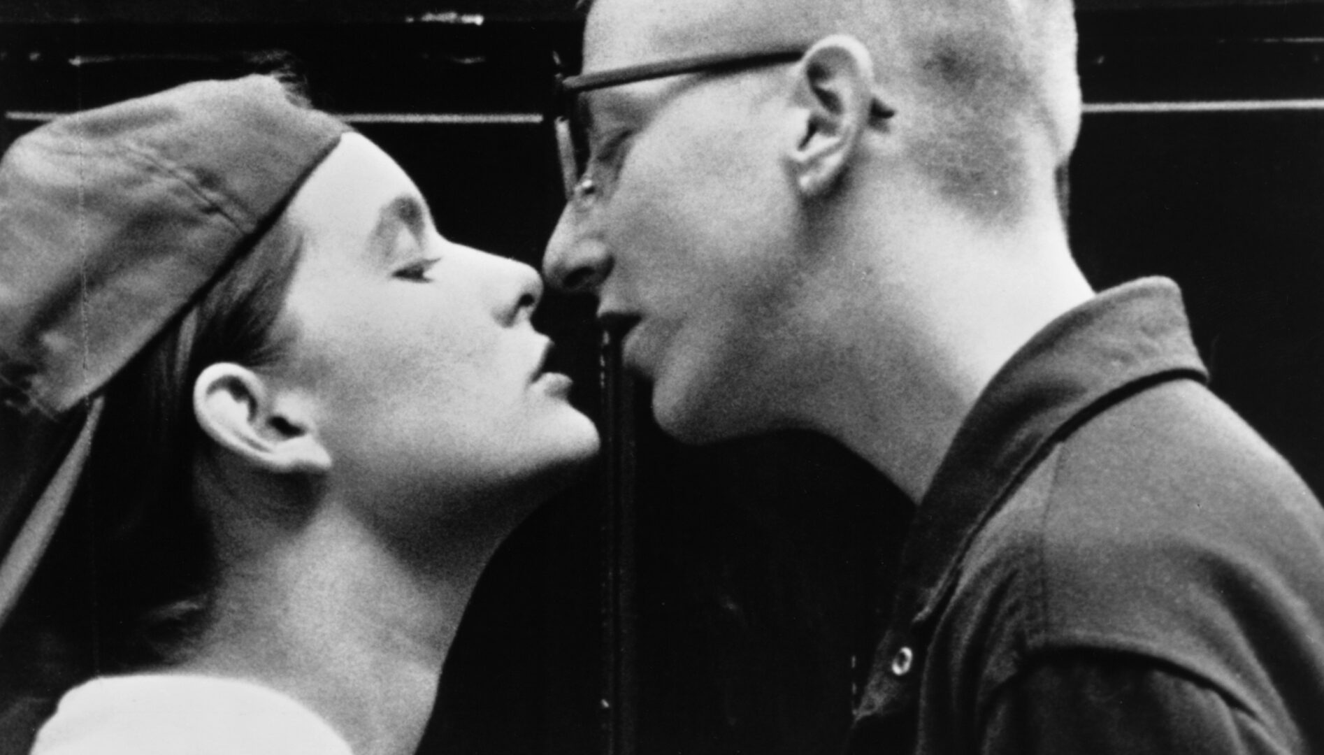 Black and white film still of two women about to kiss.