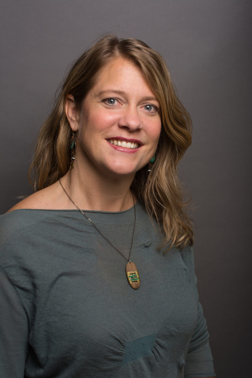 Photo of a smiling woman with long dark blonde hair.