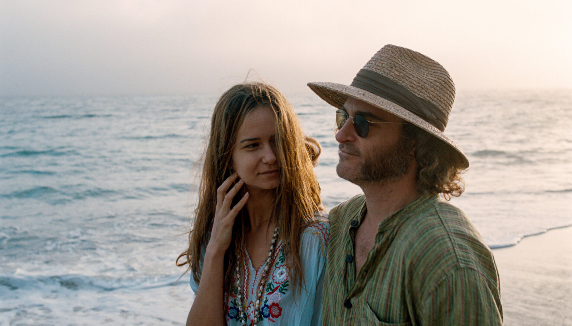 A man and a woman walking on a beach.