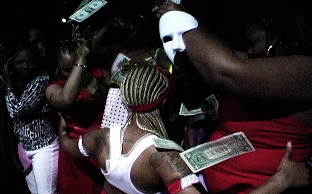 Photo of people dancing, some wearing masks and throwing money.