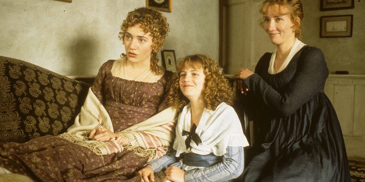 A group of two women and a girl in 19th century dresses in a living room.