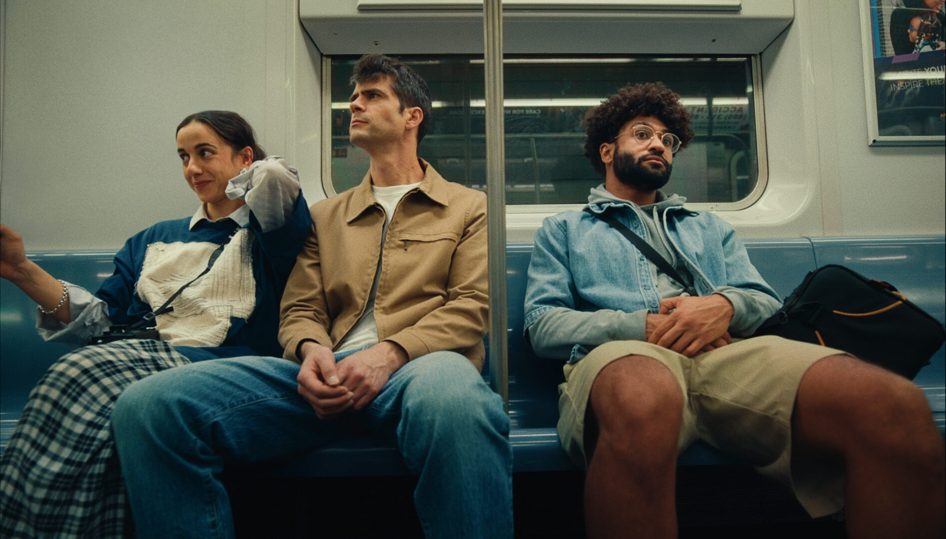 Three people sitting on a subway.