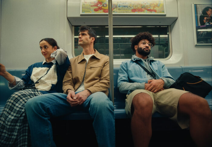 Three people sitting on a subway.