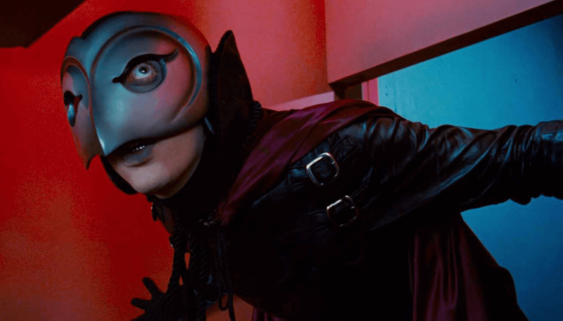 A person in a phantom mask and leather costume.