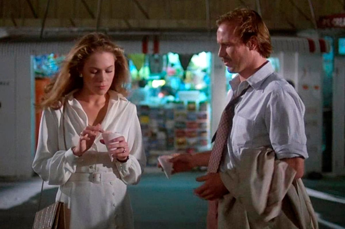 Film still of a nighttime scene where a woman with blonde hair and a white button-down shirt is talking to a man with a blue button-down shirt and a tie.
