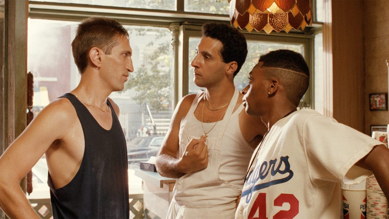 Three men talking in a pizza parlor.