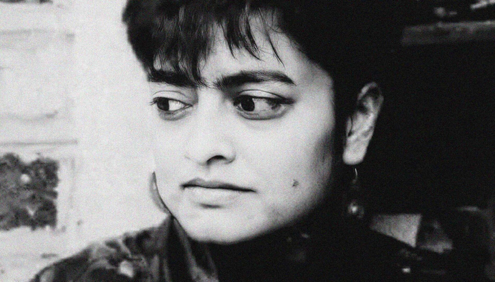 Black and white film still of a woman's face. She is looking to the side.
