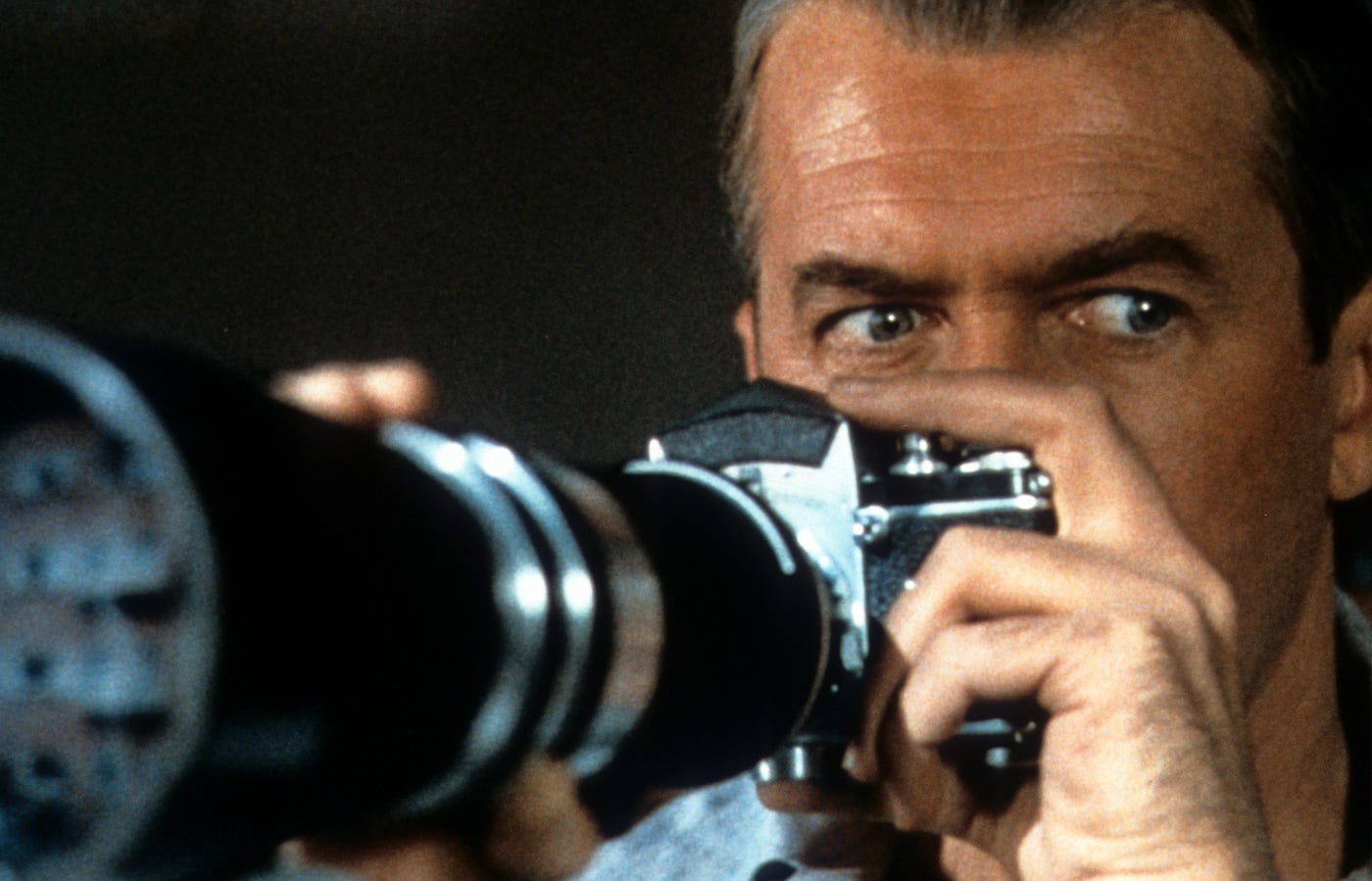 Film still of a man holding up a camera with a long lens.