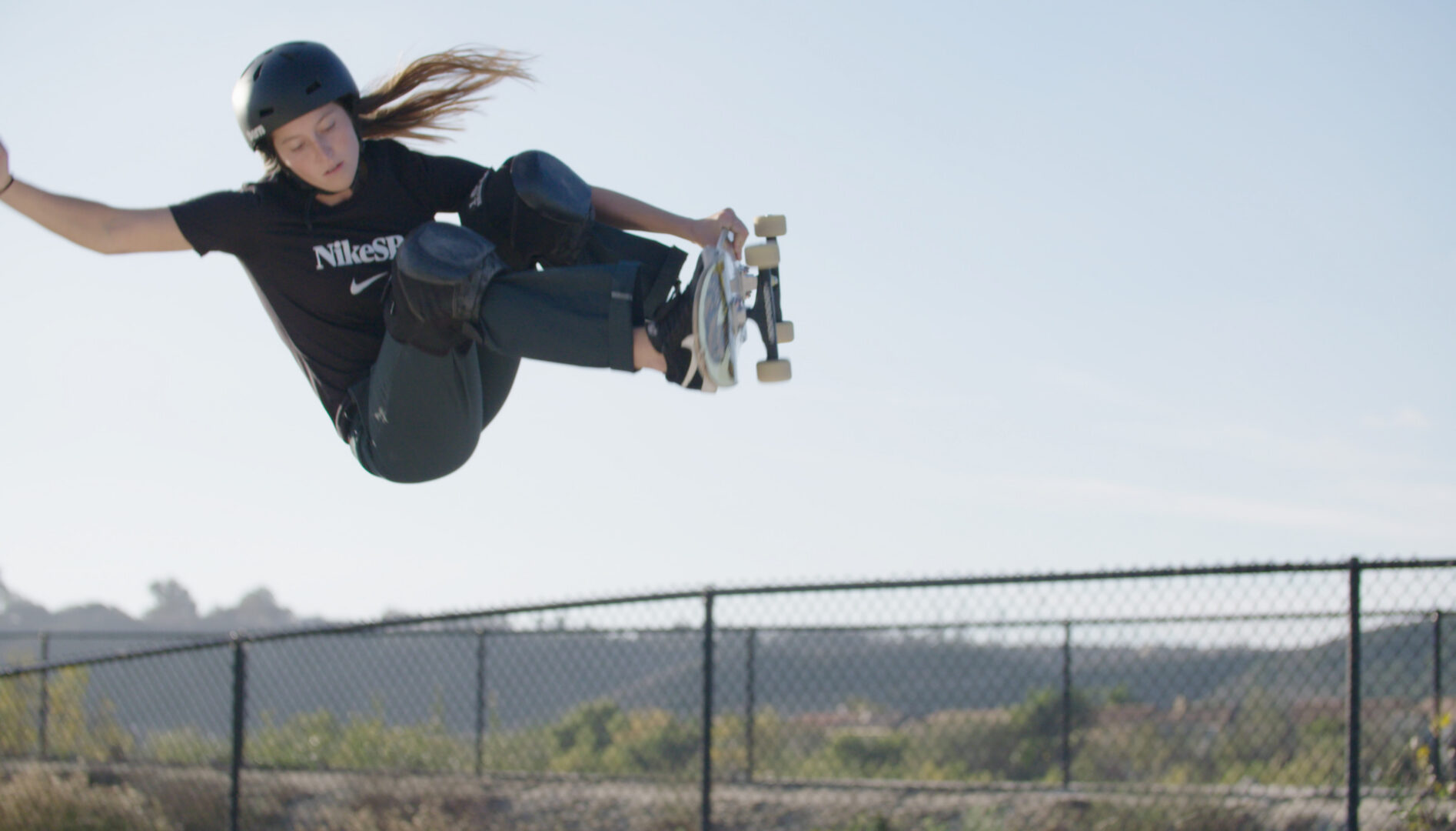 Photo of a girl mid-skateboard jump.
