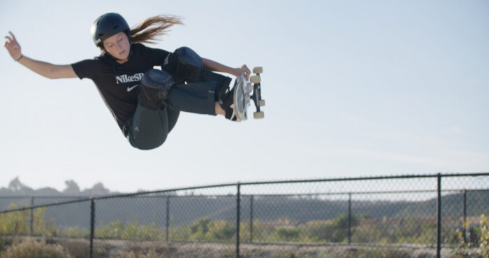 Photo of a girl mid-skateboard jump.
