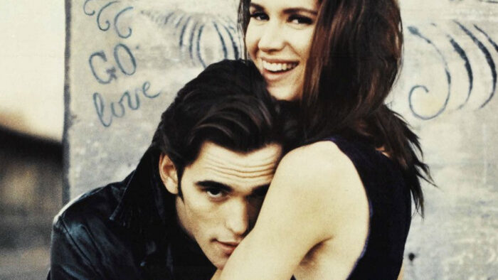 A man with dark brown hair hugging a smiling woman with long dark hair.