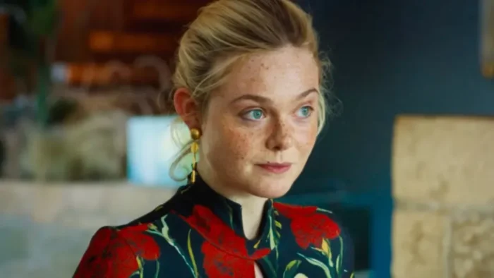 A woman with blonde hair and blue eyes, wearing a rose-printed top.