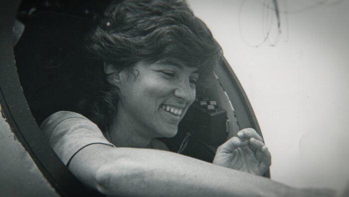 Black and white photo of a smiling woman looking off to the side.
