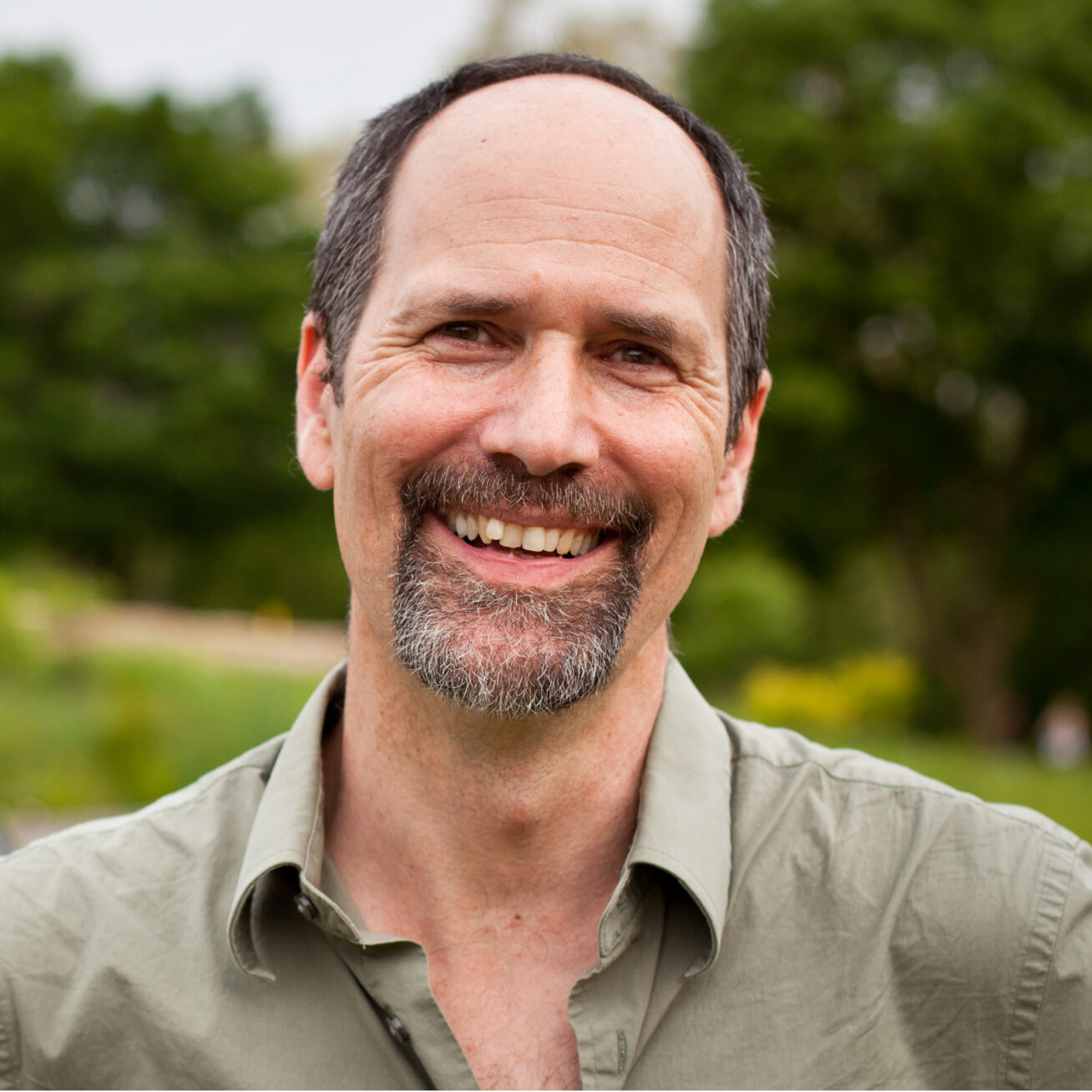 Photo of a smiling man with brown hair, a mustache, and a beard.
