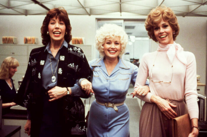 Film still of three women in an office with their arms linked