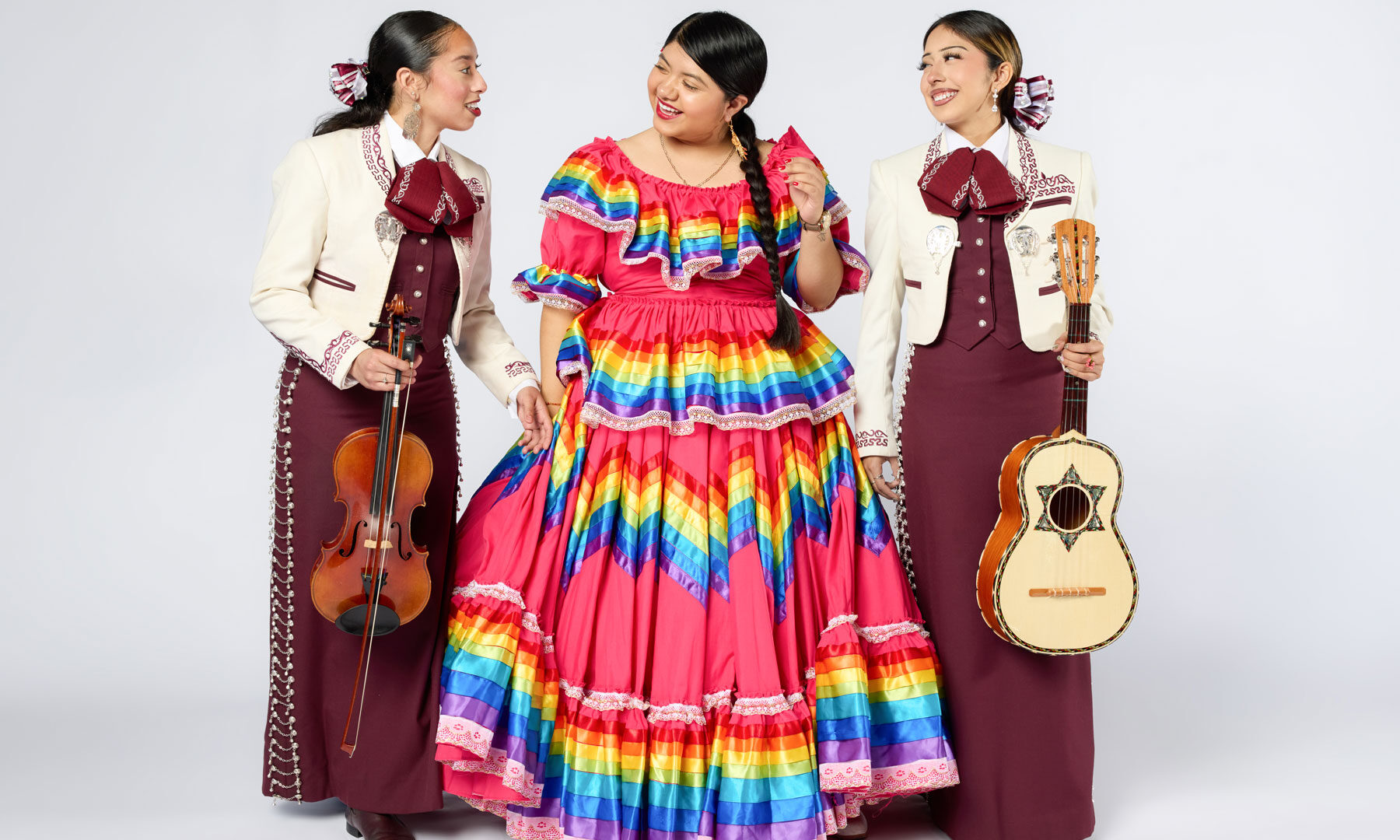 Photo of three women in traditional mariachi dresses.