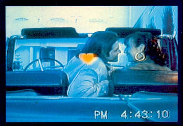 Screen shot of a couple in a car about to kiss.